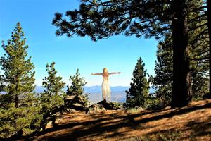 a woman stands on a rock overlooking a beautiful scene after she learns adaptive techniques. Learn how to help your clients to thrive with these CE courses about behavior disorders.