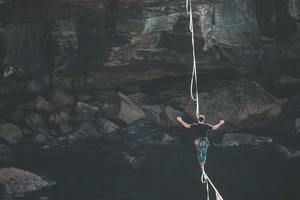 A patient navigates a risky tightrope high above a rocky shoreline in this photo. Counselling is an area where we shouldn't stray away from difficult challenges, and it is important to gain visibility into and mitigate risk.
